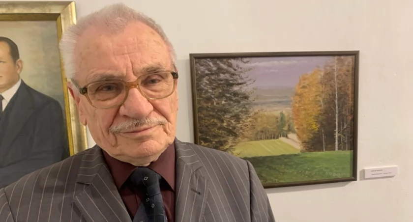 Marian Matłok na tle swoich obrazów w Galerii Sztuki MOK.