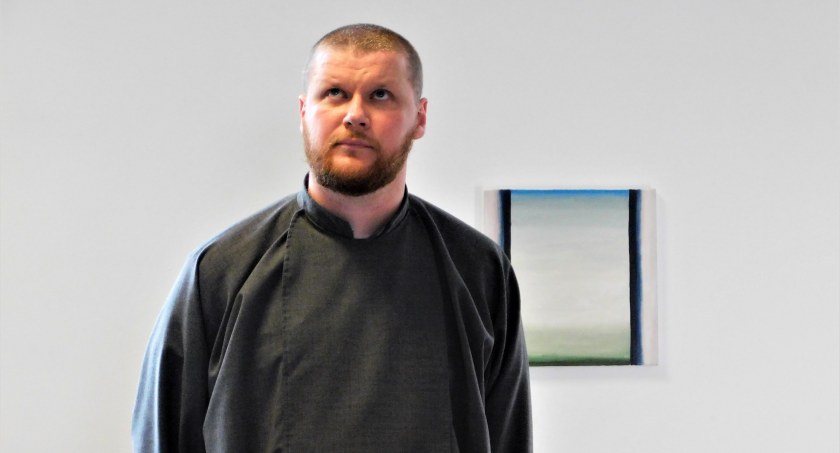 Piotr Albert Koczaj podczas wernisażu w Galerii Sztuki MOK. W tle jedna z jego prac.